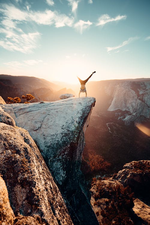 paesaggio con irradazioni del sole con uomo sullo sfondo in verticale su una roccia 