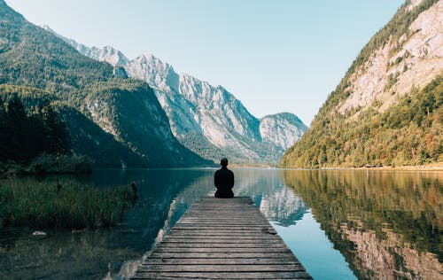  persona seduta su un pontile di un lago di Montagna